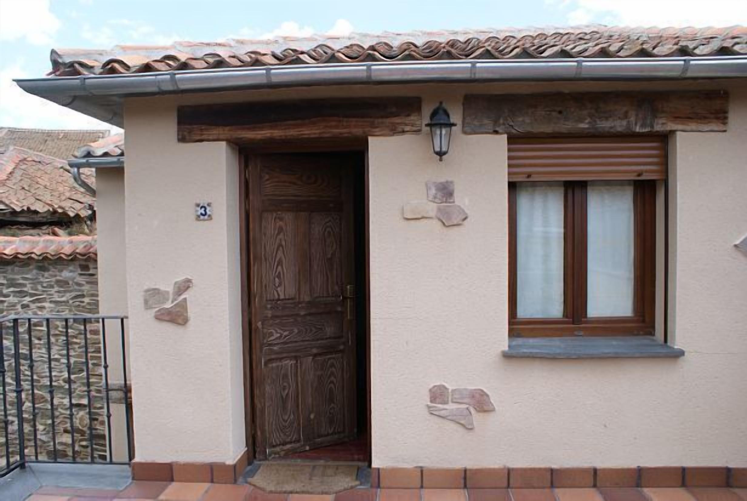 Un edificio con puerta de madera, ventana con persiana y pared de piedra.