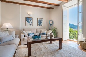A living room with a sofa, coffee table, and a view of the outdoors. - Can Busquera (Sóller)