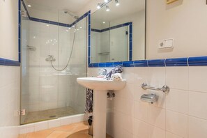 Een badkamer met een douchecabine van glas, een wastafel met spiegel en een handdoekhouder.