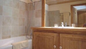 A bathroom with a wooden vanity, a bathtub, and a shower.