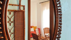 A mirror with a wooden frame reflecting a room with a sofa, chairs, and a window with curtains. - Panarea House - Detached cottage by the sea (Marina di Modica - Modica)