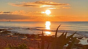 A sunset over a rocky beach with sparse vegetation. - Panarea House - Detached cottage by the sea (Marina di Modica - Modica)