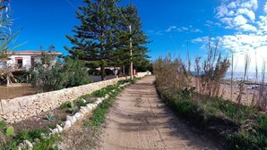 A dirt path leading to a beach, flanked by a stone wall and vegetation. - Panarea House - Detached cottage by the sea (Marina di Modica - Modica)