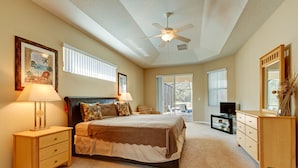 A bedroom with a bed, bedside tables, a ceiling fan, and a large window. - Spacious Exec Villa With Large Private Pool. Stunning Golf Course and Lake Views (Davenport)