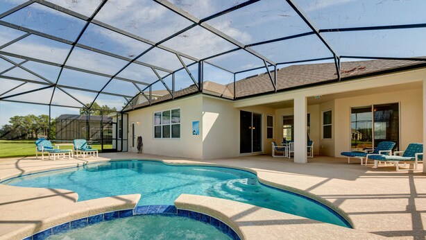 A covered outdoor swimming pool with lounge chairs and a house in the background. - Spacious Exec Villa With Large Private Pool. Stunning Golf Course and Lake Views (Davenport)