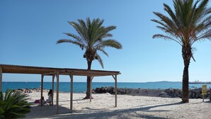 A beach with a wooden pavilion, palm trees, and a rocky shoreline. - Lovely Old Stone Bastide With Private Pool, Short Drive To Beach (Vence)