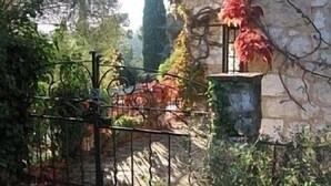 A stone building with a metal gate, surrounded by greenery and a tall tree. - Lovely Old Stone Bastide With Private Pool, Short Drive To Beach (Vence)