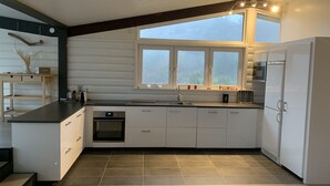 A modern kitchen with white cabinetry, a built-in oven, a large window, and a dark ceiling. - Wonderful house in Strömstad! (Strömstad)