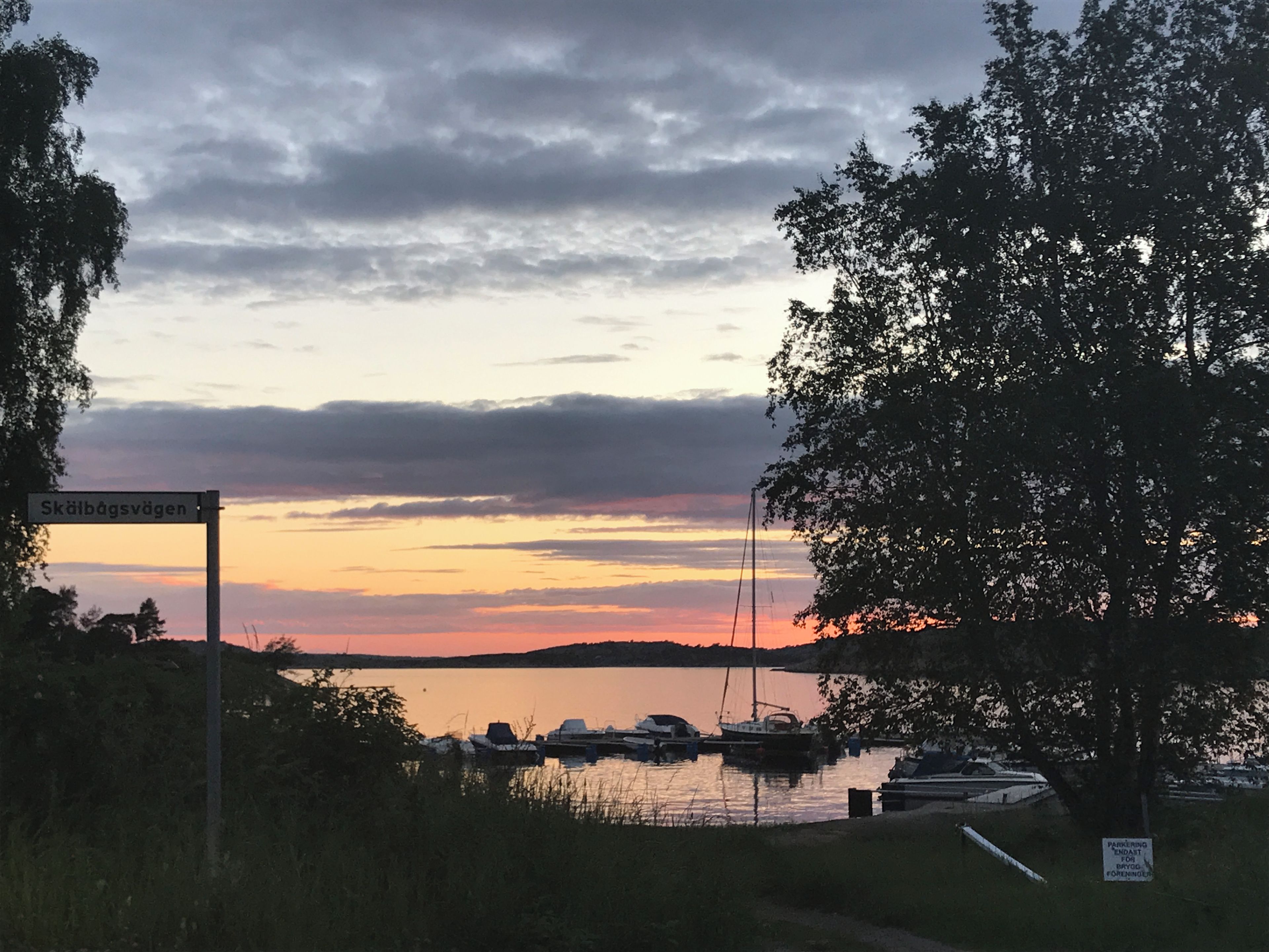 A marina with boats docked, a sign indicating parking for boats, and a cloudy sky.