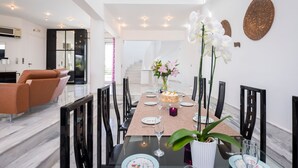 A modern dining area with a glass table, black chairs, and a vase of flowers. - Stunning villa for private Escape/ Create priceless memories! large private pool (Hania)