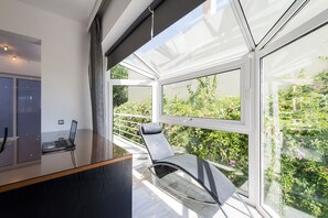 Et moderne værelse med glasvæg, en bærbar computer på et skrivebord og en stol ved vinduet.