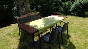 A wooden bench with a patterned backrest and a table with a green tablecloth.