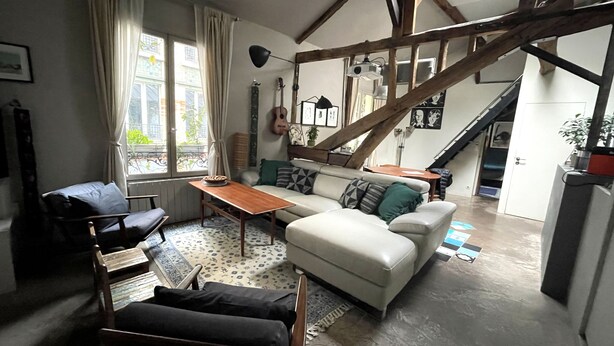 A cozy living room with a sofa, a wooden table, and a chair. There is a staircase leading to another level. - CHARMING, AIR-CONDITIONED HOUSE WITH ROOFTOP, PARIS, CANAL ST. MARTIN (Paris)