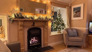 Una sala de estar acogedora con chimenea, un árbol de Navidad y un sofá cómodo.