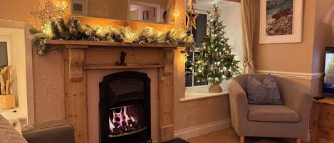 Un salon chaleureux avec une cheminée, un sapin de Noël et un canapé confortable.