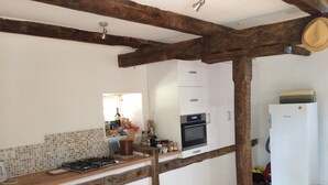 A kitchen with a tiled backsplash, wooden beams, a gas stove, a built-in oven, and a white refrigerator. - NEW: Barn conversion in a fantastic village in the Lot (Limogne-en-Quercy)