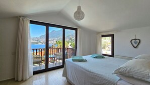 Une chambre avec un lit, une vue sur la mer et un balcon.