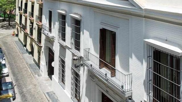 Een wit gebouw met een balkon en een raam met een metalen traliewerk.