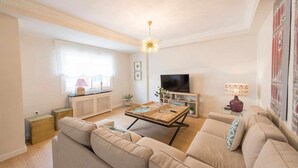 Een moderne woonkamer met een bank, een houten salontafel, een televisie en een decoratieve lamp.