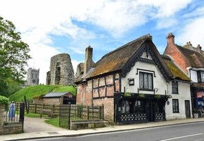 A traditional building with a black and white facade, a stone structure in the background, and a clear sky.