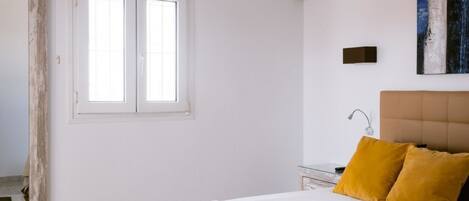 A bedroom with a bed, a nightstand, a mirror, and a window.