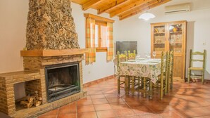 Un comedor con chimenea, una mesa dispuesta para cuatro personas y un aparador con puertas de vidrio.
