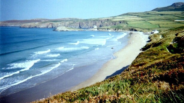 A coastal landscape with a sandy beach, grassy hills, and cliffs. - Cosy Cottage. Log Stove, Private Walled Garden, Coastal Walking From The Door. (St Davids)
