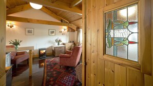 A cozy room with wooden beams, a fireplace, a patterned rug, and a stained glass window. - Cosy Cottage. Log Stove, Private Walled Garden, Coastal Walking From The Door. (St Davids)