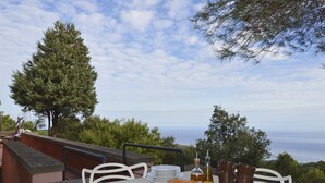 An outdoor dining area with a table set for two, a bottle of olive oil, and a loaf of bread. - House with pool, sea views near Cefalu and Castelbuono and beach 10 minutes (Pollina)