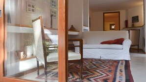 A living room with a white sofa, a patterned rug, and a wooden chair. - House with pool, sea views near Cefalu and Castelbuono and beach 10 minutes (Pollina)