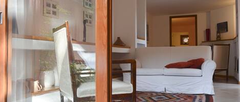 Un salon avec un canapé blanc, un tapis à motifs et une chaise en bois.