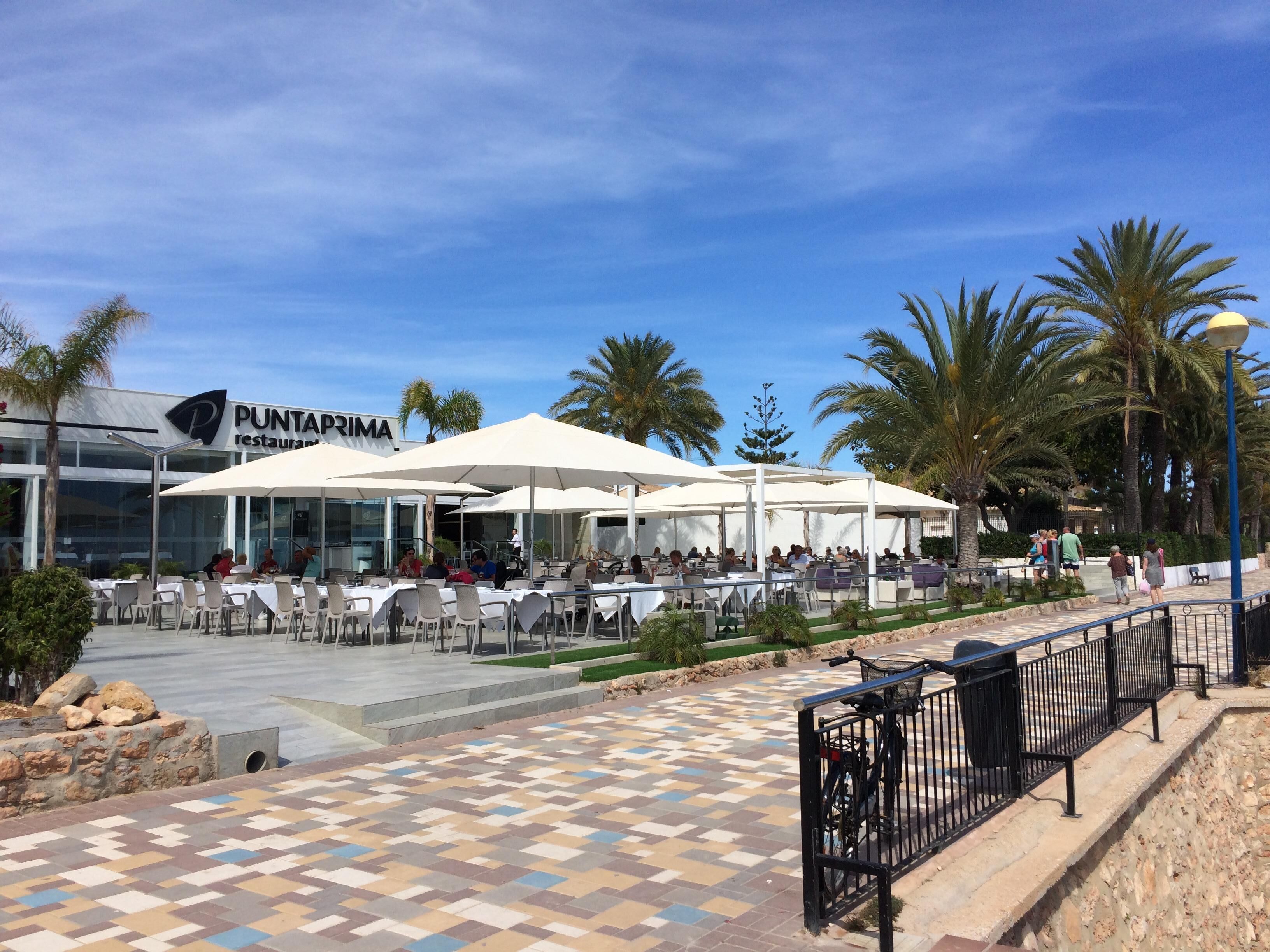An outdoor dining area with tables and umbrellas at Punta Prima restaurant.