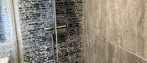 A shower with a modern design, featuring a stone-like wall and a sleek, metallic showerhead.