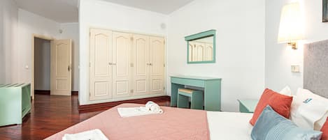 A hotel room with a bed, a desk, a wardrobe, and a mirror.