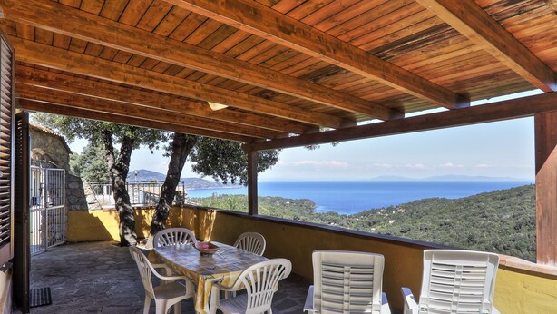 A covered patio with a table and chairs, overlooking a scenic view of the sea and hills. - Colle Paradiso Island of Elba from the tranquility of nature to the sea in 10 minutes (Capoliveri)