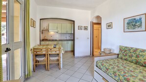 A compact living space with a dining area, kitchenette, and a sofa with a floral cover. - Colle Paradiso Island of Elba from the tranquility of nature to the sea in 10 minutes (Capoliveri)