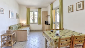 A room with a bed, a desk with a computer, a dining table with chairs, and a window with curtains. - Colle Paradiso Island of Elba from the tranquility of nature to the sea in 10 minutes (Capoliveri)
