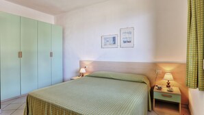 A bedroom with a bed, nightstand, lamp, and wardrobe. - Colle Paradiso Island of Elba from the tranquility of nature to the sea in 10 minutes (Capoliveri)