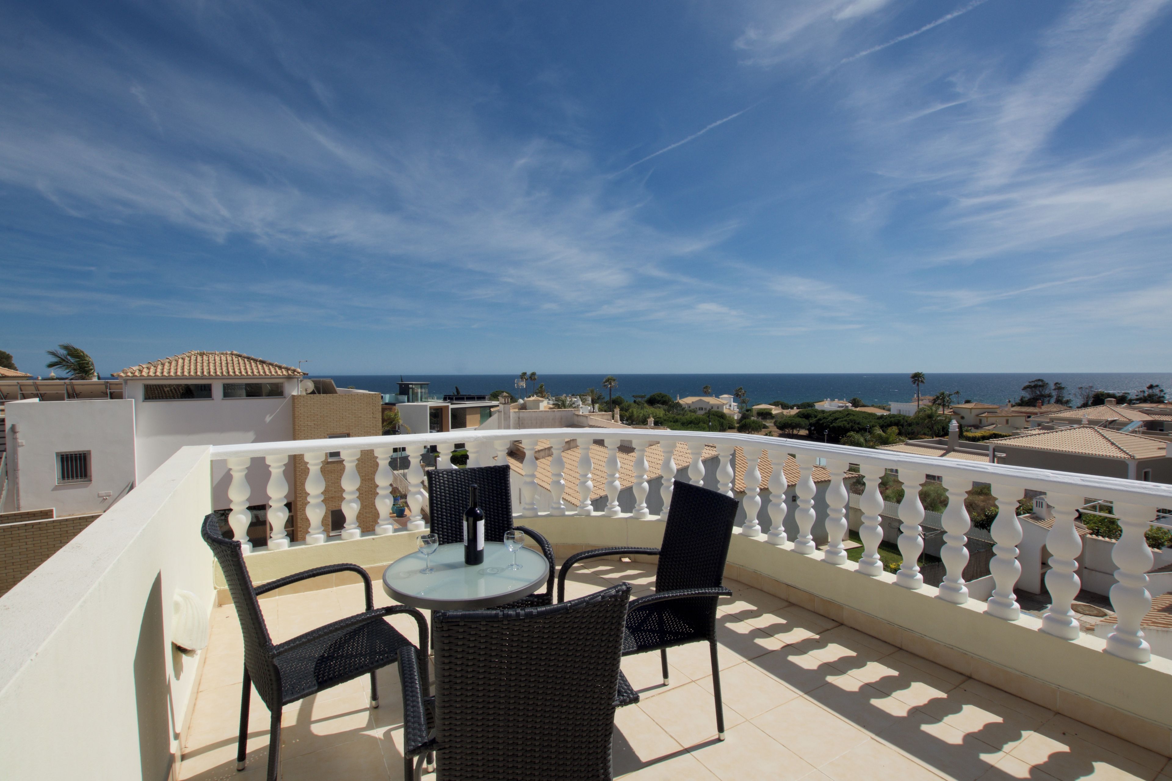 Un balcon avec une table et des chaises, offrant une vue sur la côte.