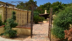 A gated entrance with a decorative iron gate, a stone pathway, and surrounding greenery. - PINARELLO, near PORTO VECCHIO, air-conditioned, garden, swimming pool, beach 500 meters. (Saint Lucie de Porto Vecchio)