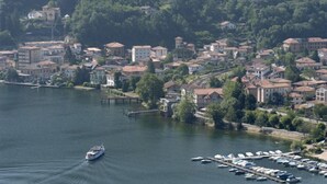 Un port de plaisance où sont amarrés des bateaux, entouré d’un quartier résidentiel avec des maisons et des arbres.