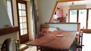 Ein gemütlicher Essbereich mit Holztisch und -stühlen, einer Couch und einer Küche im Hintergrund.