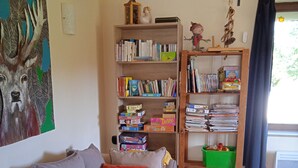 Ein gemütliches Wohnzimmer mit einer Couch, einem Bücherregal und einem kleinen Tisch.