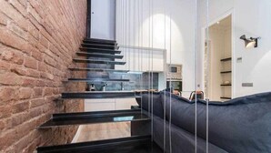 A modern staircase with a black railing leading to a kitchen area. - Stylish Apartment C in city center (Barcelona)