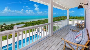 A wooden deck with a pool, white railings, and a view of the ocean. - Relaxation, Seclusion and Luxury -  beachfront and poolside (Little Exuma)