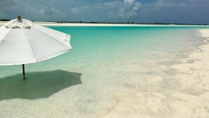 A beach with clear turquoise water and a white umbrella. - Relaxation, Seclusion and Luxury -  beachfront and poolside (Little Exuma)