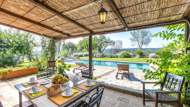Eine Terrasse im Freien mit Frühstückstisch, mit Blick auf einen Swimmingpool und üppiges Grün.