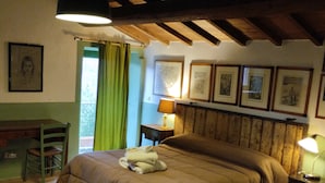 Ein Schlafzimmer mit hölzernem Kopfteil, einem Bett mit brauner Bettdecke, einem Schreibtisch mit Stuhl, einer Lampe und gerahmten Bildern an der Wand.