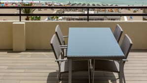 An outdoor seating area with a table and chairs, overlooking a beach with umbrellas and people. - PREMIUM 3 BEDROOMS PENTHOUSE BEACHFRONT IN TORREMOLINOS  (Torremolinos)