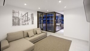 A modern living room with a beige sofa, a large framed cityscape picture, and a glass door leading to an outdoor balcony. - PREMIUM 3 BEDROOMS PENTHOUSE BEACHFRONT IN TORREMOLINOS  (Torremolinos)